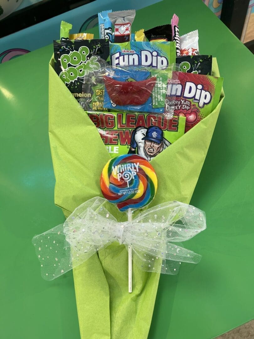 A green table with a bouquet of candy and lollipops.