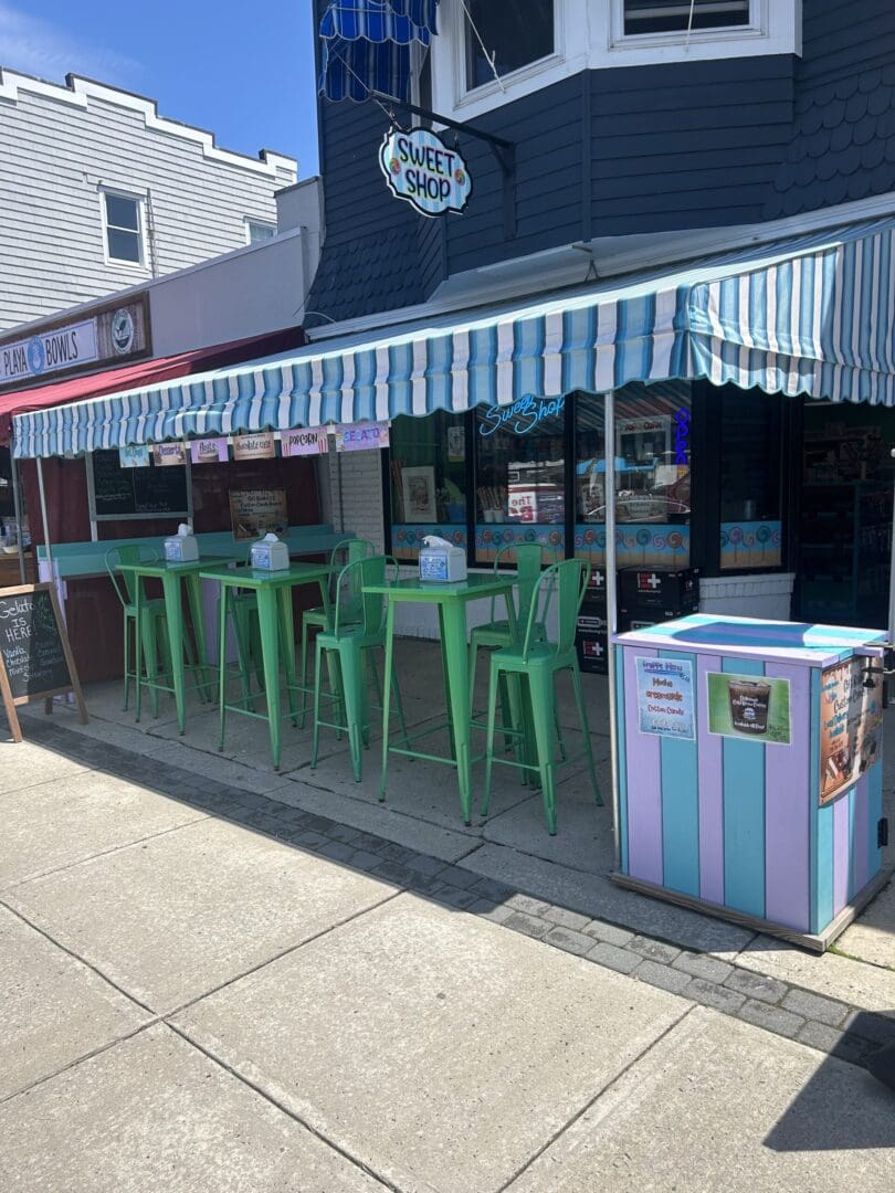 Outdoor seating area with green bar stools and a striped awning.