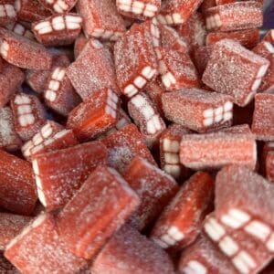 Close-up of red and white rectangular candies coated with sugar.