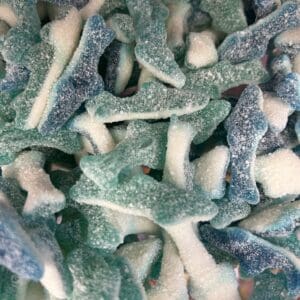 Close-up of blue and white gummy shark candies scattered together.