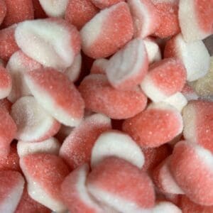 Close-up of pink and white gummy shark candies piled together.