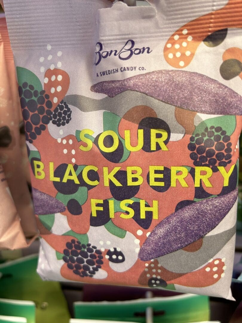 Colorful packaging for sour blackberry fish candy with berry illustrations.
