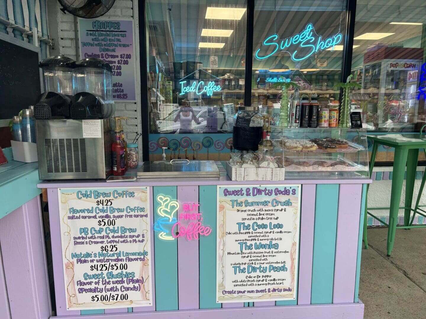 Colorful window display with menu signs and neon lights at a shop.